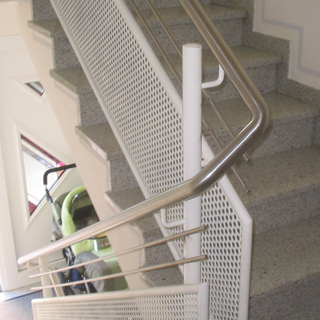 Eine Treppe mit weißem Geländer und einem grünen Kinderwagen auf der untersten Stufe.