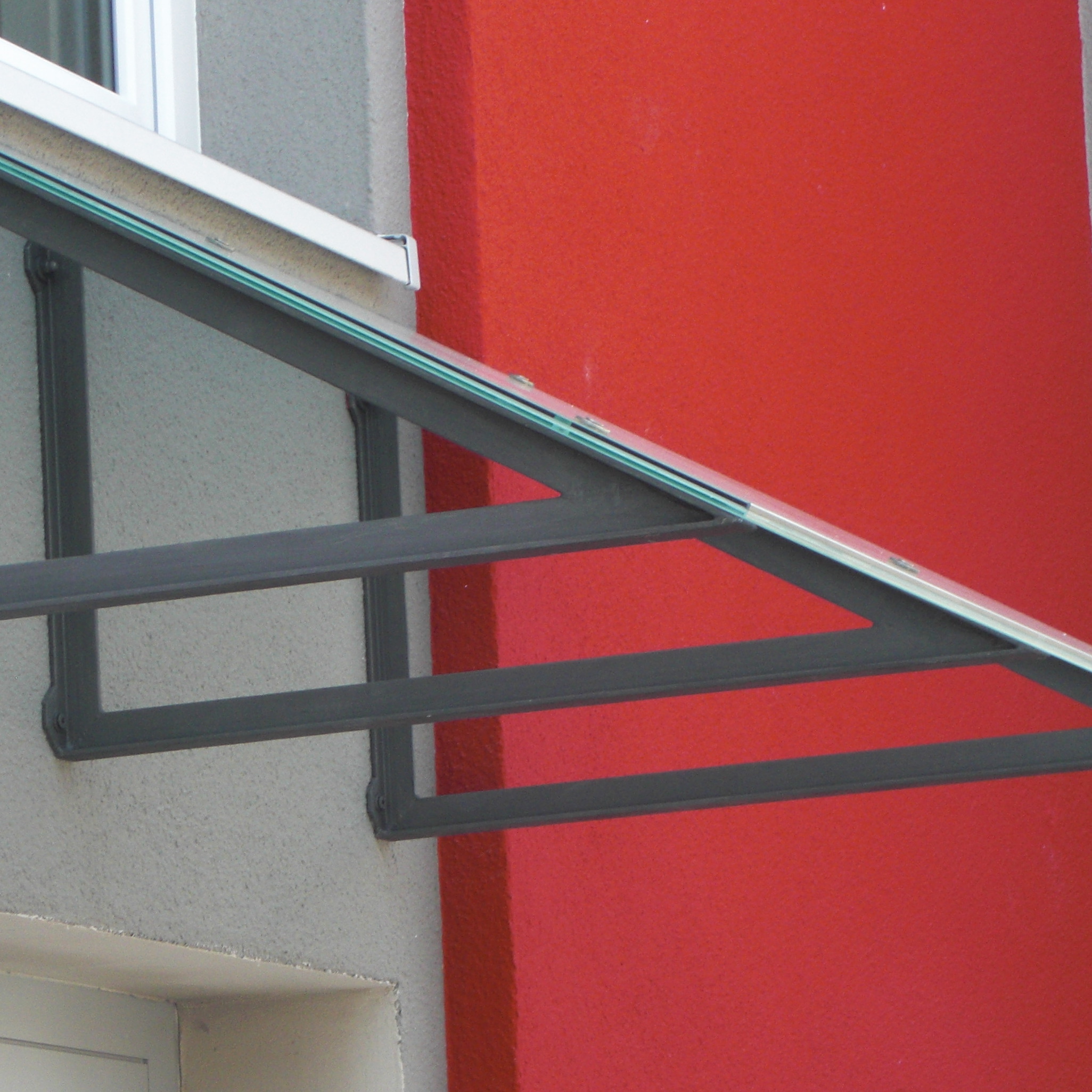 An der Seite eines Gebäudes wird ein Vordach angebracht.